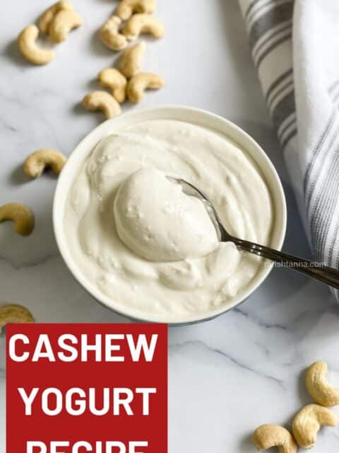 A bowl of vegan cashew yogurt is on the table with a spoon inserted.